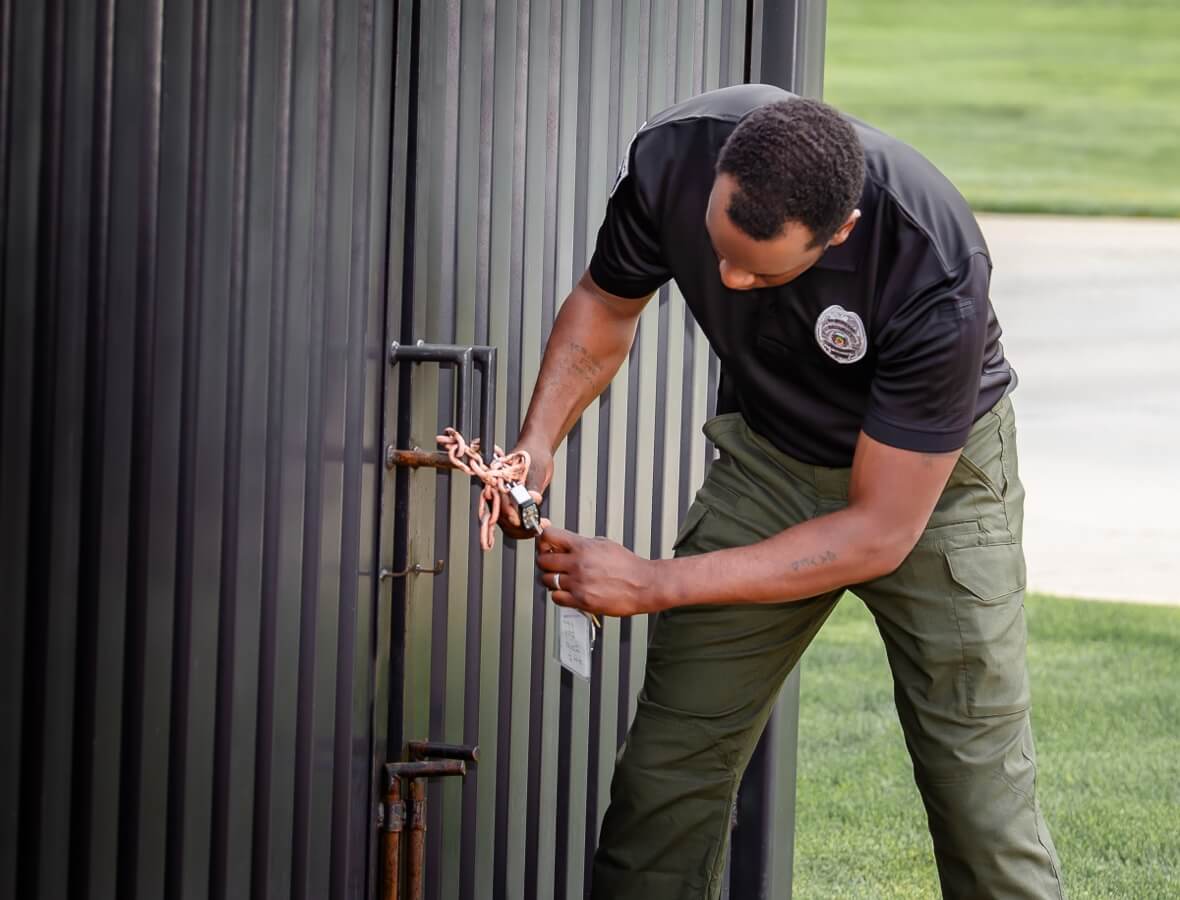 A man unlocking a gate, symbolizing access control and security management services provided by 5th Meridian Group.