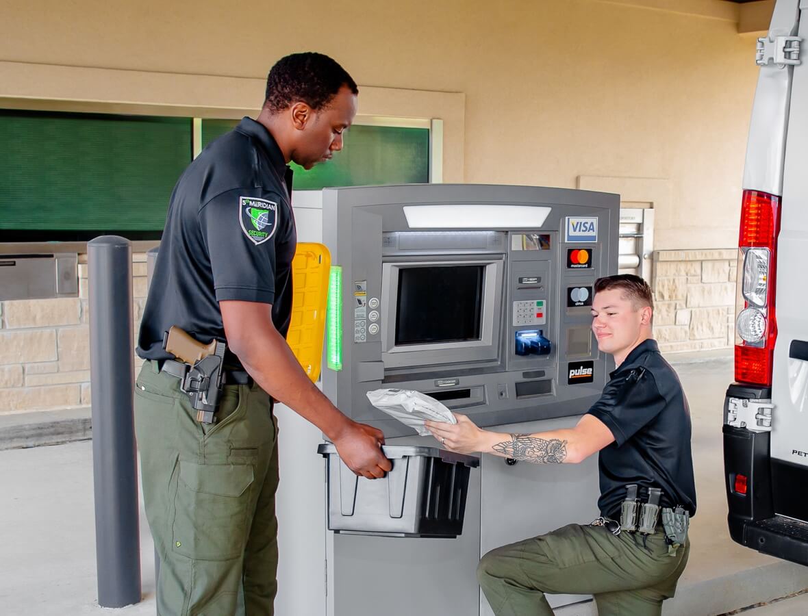 Two security guards from 5th Meridian Group servicing an ATM, ensuring functionality and security for financial transactions.